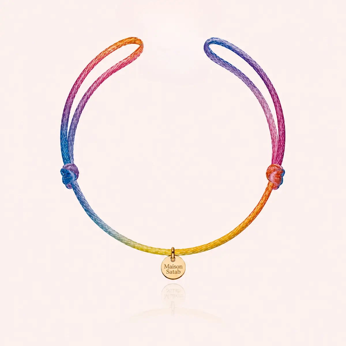Bracelet en cordon dégradé rose, orange, bleu et jaune, noué et orné d’une médaille dorée — Maison Satab