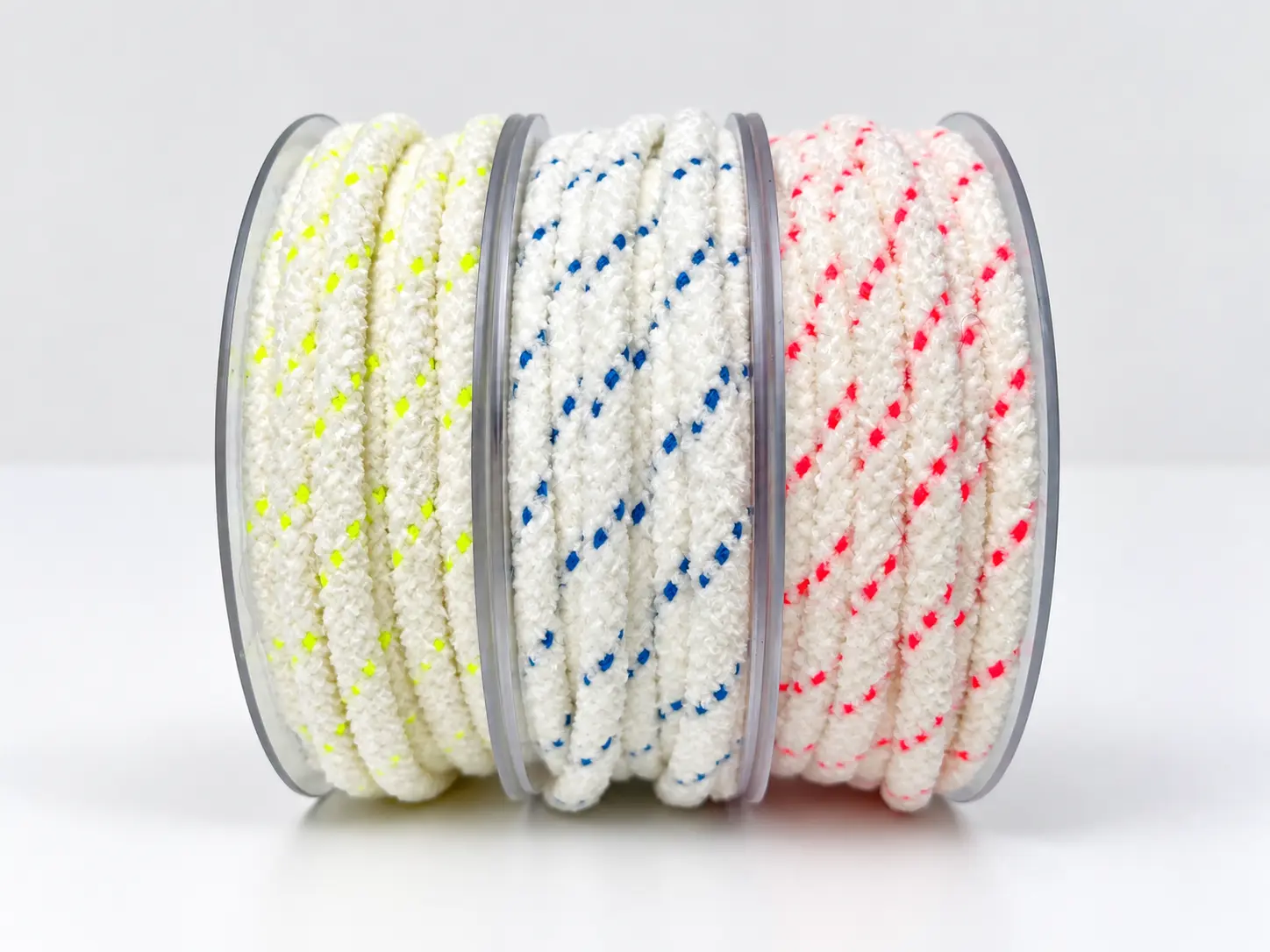 Trois bobines de cordons tressés blancs chinés de jaune fluo, bleu et rouge — Maison Satab